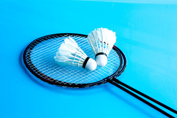 .two  badminton racket and shuttlecock on sky blue field background.