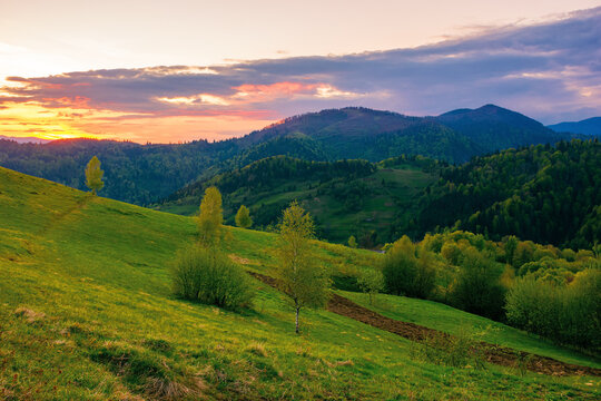 rolling rural mountain landscape at dusk. gorgeous nature scenery in spring. clouds on the sky in evening light