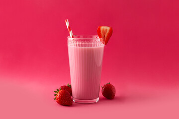 Strawberry milkshake in glass on pink background