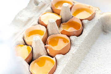 Close-up of fresh chicken eggs yolks in a shell on cardboard tray. 