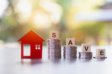 Savings. Investing in real estate. Graph of the growth of a pile of silver coins and a red wooden house. Loans to buy a home. Wooden letters blocks writing words notes Save for the future.