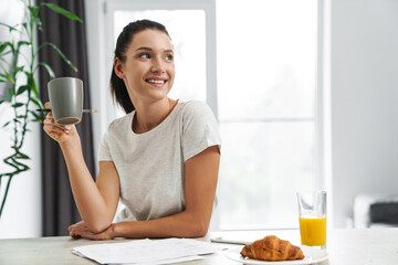 European young woman drinking coffee while having breakfast