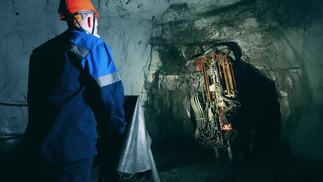 Miner is operating a boring mechanism to irrigate a tunnel