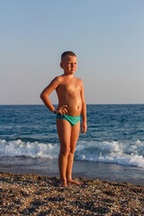 Fototapeta na wymiar nine-year-old boy in bathing trunks stands by the sea