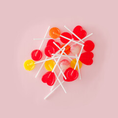 A bunch of lollipops lying on the pastel pink background. Creative colorfool layout.
