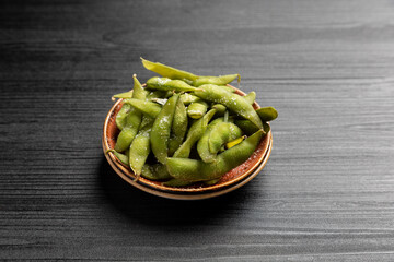 Japanese appetizer edamame, soy pods on dark background.