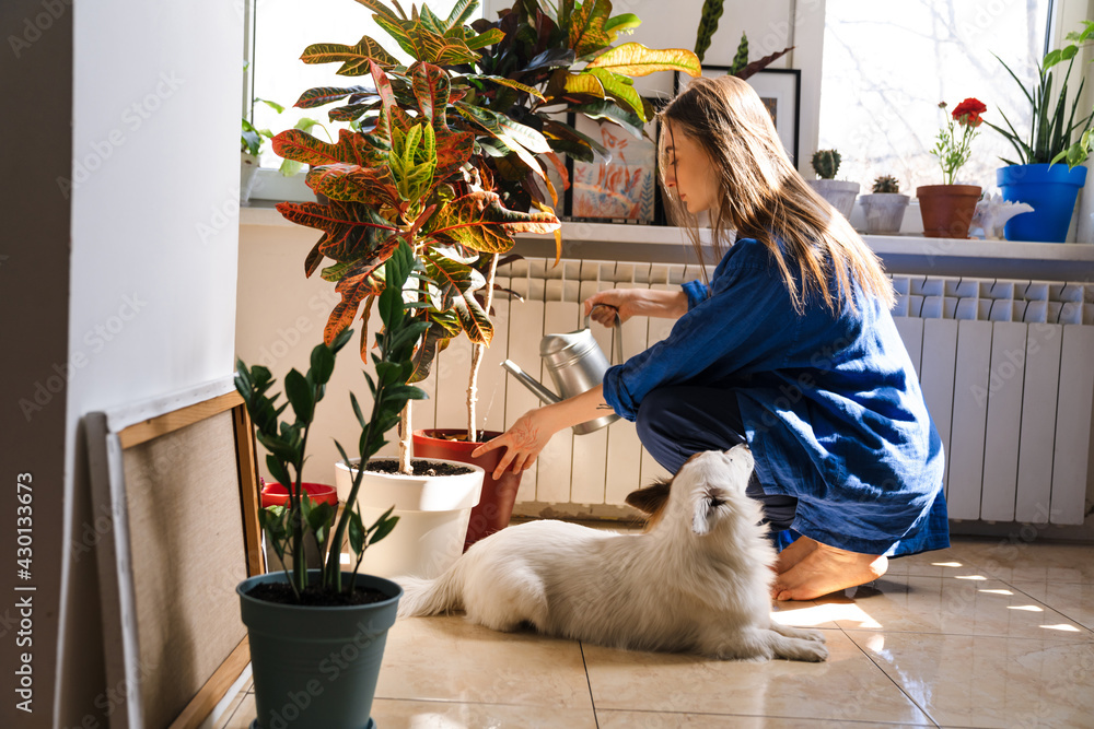 Wall mural Young woman florist taking care of pot plants