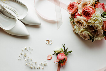 Pink flowers, pearl jewelry and two gold wedding rings on a white background. Wedding concept. Isolated	