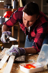 Young male carpenter working in workshop. Carpenter working on wood craft at workshop.