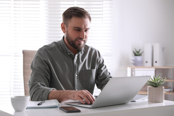 Young man working on laptop at table in office