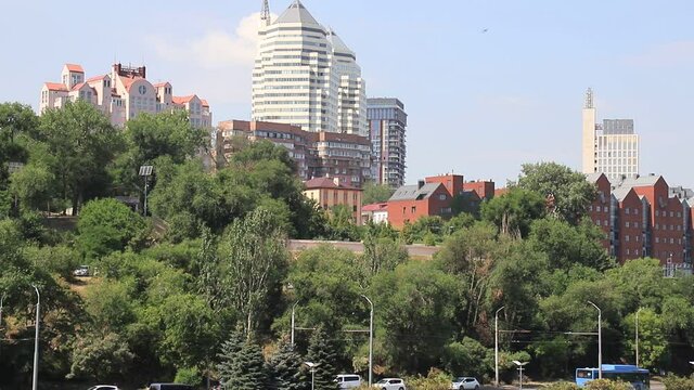 ars go along the street against the background of buildings, towers, skyscrapers, park in the city  Dnepropetrovsk, Dnipro, Ukraine. Beautiful view from Monastyrsky Island in spring and summer
