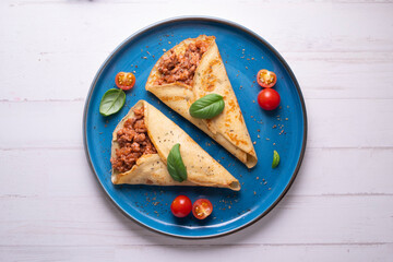 Crepes stuffed with bolognese sauce and basilicum leaves