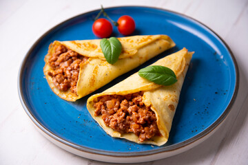 Crepes stuffed with bolognese sauce and basilicum leaves