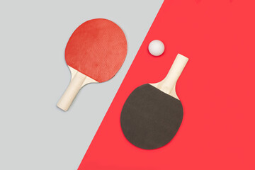 Raquetas de ping-pong con una pelota sobre un fondo gris y rojo liso y aislado. Vista superior. Copy space. Concepto: Deportes