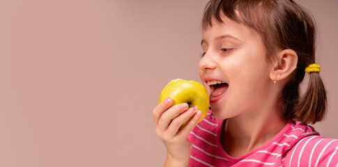 Fototapeta na wymiar Profile portrait of a happy child girl with apple as symbol of diet and healthy food. Copy space for design.