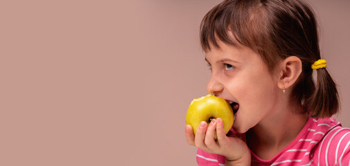 Fototapeta na wymiar Profile portrait of a serious child girl with apple as symbol of diet and healthy food. Copy space for design.