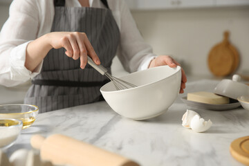 Fototapeta na wymiar Woman making dough at table in kitchen, closeup
