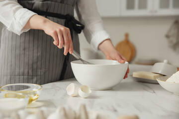 Woman making dough at table in kitchen, closeup