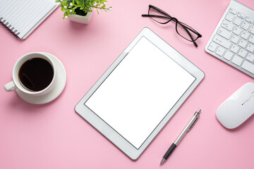 Top view of desk pink background with tablet blank white screen and office equipment. Copy space.