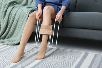 Woman wearing compression tights with donner on sofa indoors, closeup. Space for text