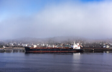 Large oil tanker at a commercial pier in Maine on a foggy day