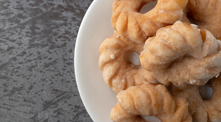 Cruller shaped donuts on a white plate overhead close view