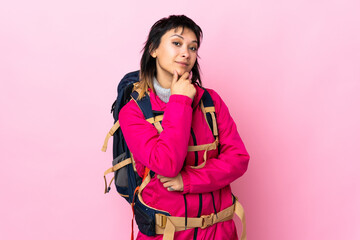 Young mountaineer girl with a big backpack over isolated pink background laughing