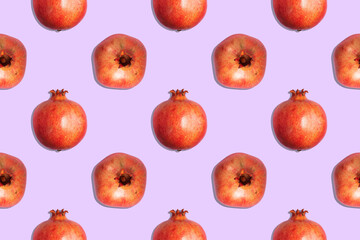 Seamless pattern of juicy red pomegranates on a purple background