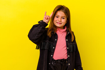 Little caucasian girl isolated on yellow background showing a horns gesture as a revolution concept.