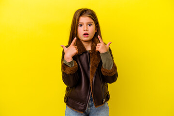 Little caucasian girl isolated on yellow background pointing upside with opened mouth.