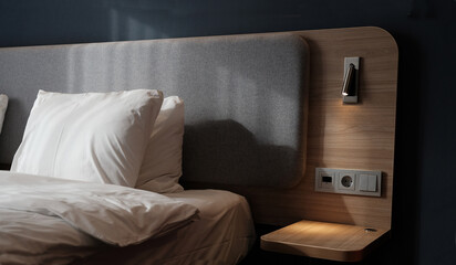 Close-up fragment of bedroom with empty bedside table, reading lamp and a USB socket in modern...