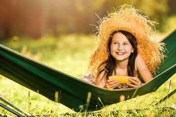 Cute little girl resting in a folding hammock. Season of summer picnics and weekends. Side place for text, ads, positive news. Summer camp for children.