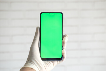  hand in latex gloves holding smart phone with green screen 