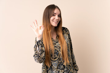 Young caucasian woman isolated on beige background showing ok sign with fingers