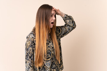 Young caucasian woman isolated on beige background with surprise expression while looking side