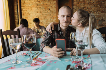 Caucasian woman kisses her partner on the cheek in restaurant.