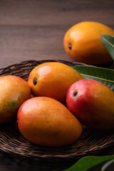 Mango. Fresh mango fruit on a bamboo sieve over dark wooden table background.