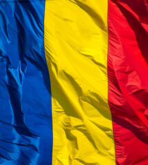 The flag of Romania in the wind. Waves. Red, yellow and blue.Close up.