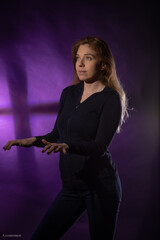 woman playing invisible piano next to the purple wall 