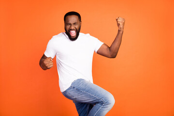 Photo of cheerful positive dark skin man winner celebrate good mood isolated on orange color background