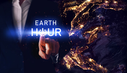Earth Hour. Hand pressing power start button. Global holiday. Futuristic night Planet Earth in dark outer space.  Elements of this image furnished by NASA. 