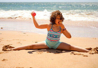 A girl on the Atlantic ocean makes a twine, holds a dumbbell in the other hand holding an apple.
