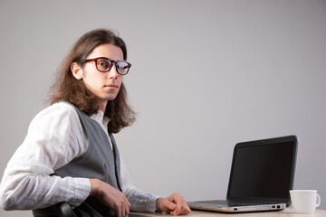 Programming and application development, a young man writes code sitting at a laptop.