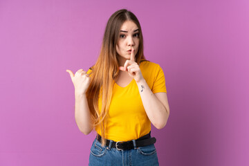 Young caucasian woman isolated on purple background pointing to the side and doing silence gesture