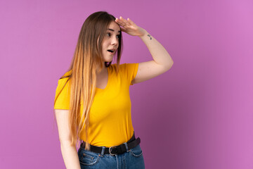 Young caucasian woman isolated on purple background with surprise expression while looking side