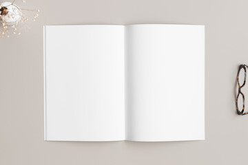 Open magazine mockup with a glasses and gypsophila on the beige table.