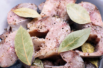 Close-up of slices of lightly salted mackerel fish with allspice and bay leaf.