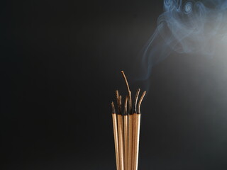 Burning incense, white smoke, black background, used as a worship background image, a sacred object...