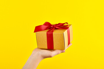 Presentation of buying a surprise with a child's hand. A gift is held on a yellow background. Delivery of orders