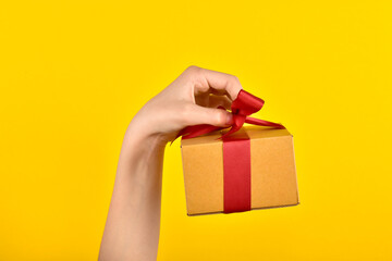 The child holds a surprise box by the ribbon. A gift is held on a yellow background. Delivery of orders